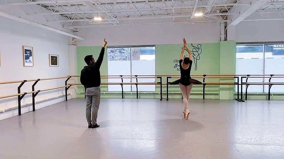 Ballet instructor coaching a student during a pointe training class in a professional studio.